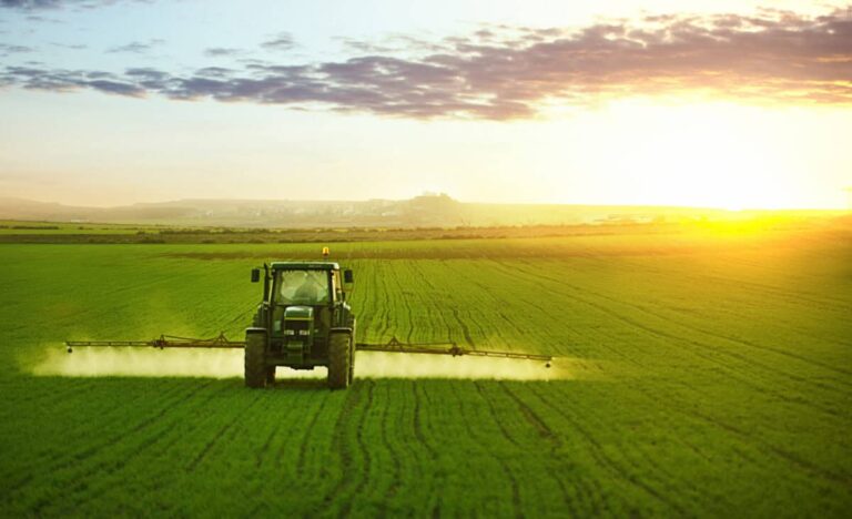 Tractor spraying a field of wheat with fertilizer